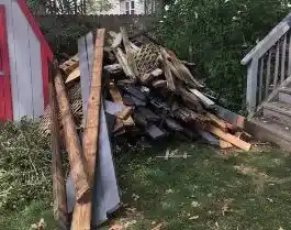 huge pile of deck boards beside a shed awaiting deck board disposal